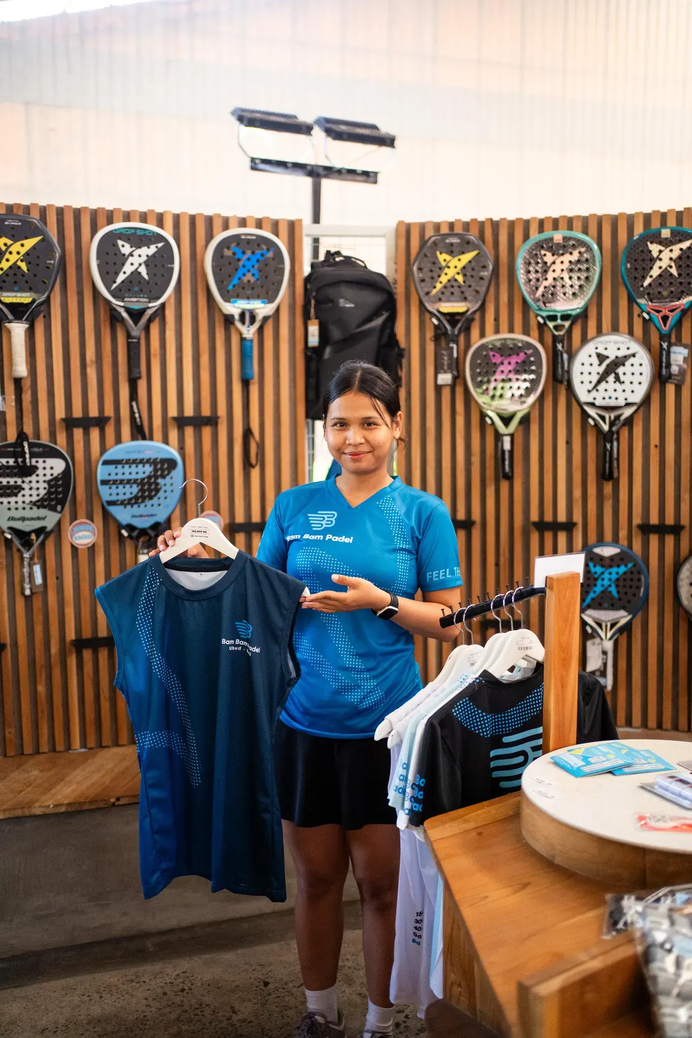 A pro-shop team member showing Bam Bam Padel club apparel