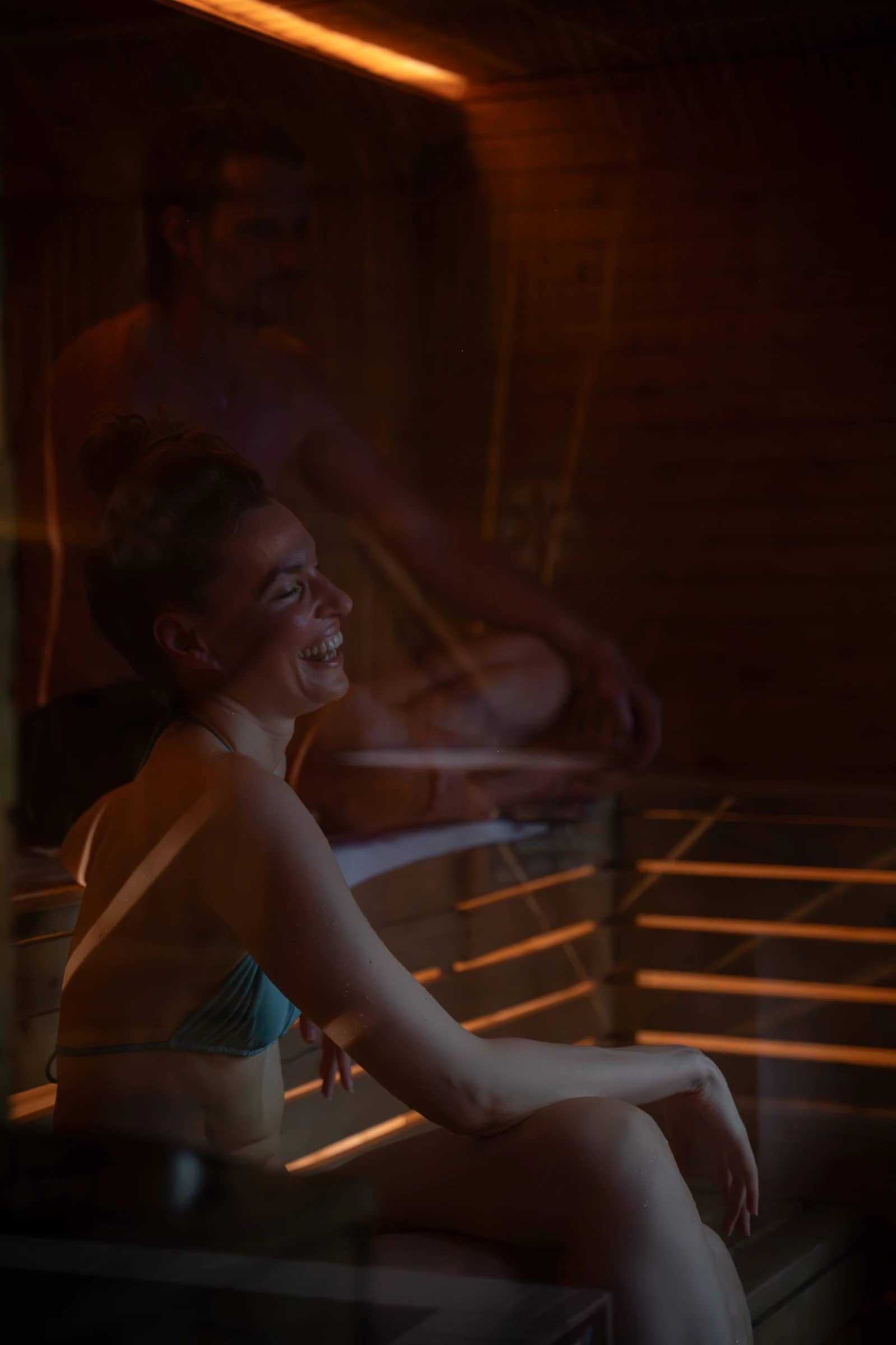 Two guests sitting on the wooden benches inside the Finnish sauna at Bam Bam Padel